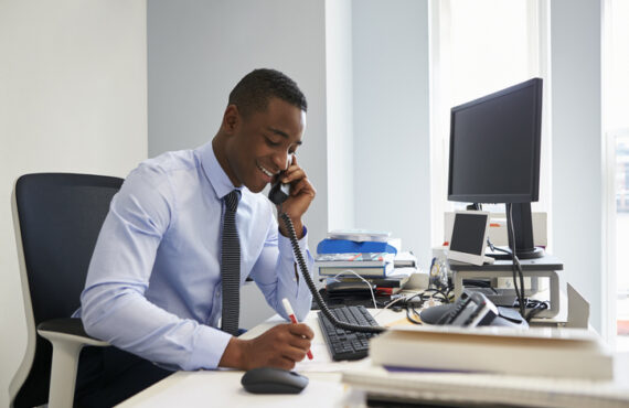 Young black businessman using the phone at his office desk Young black businessman using the phone at his office desk